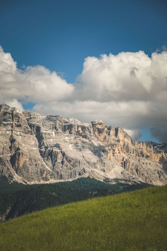 A vertical shot of a rocky hill and a cloudy sky