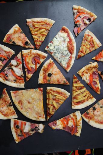 A vertical top view of different pizza slices with black background