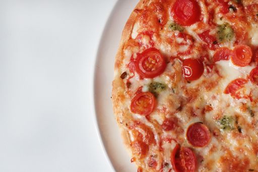 An overhead shot of a Margherita pizza on a white plate on a  white surface