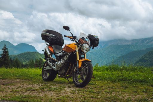 A motorcycle parked on grassland in background of greenery mountains