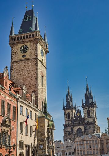 A vertical shot of castle with clock under blue bright sky in Prague