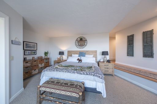 A nicely furnished room with bed, armchair, rug, beautiful lampshades and pictures