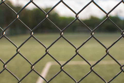 A closeup shot of a fence around a green football field