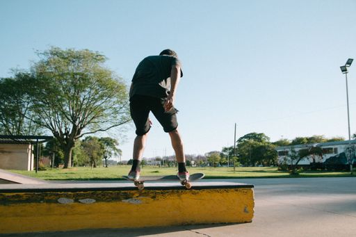 A young Caucasian man doing a stunt on a skateboard in a skate park