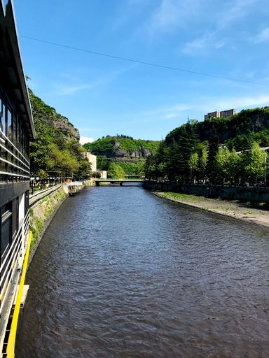 A vertical shot of a river flowing through the city with a sky on the background