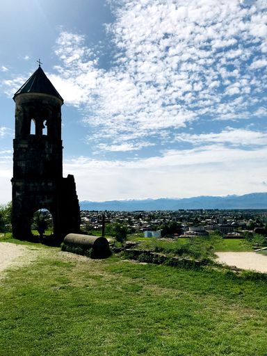 A vertical shot of a church with a bell and cloudy blue sky on the background