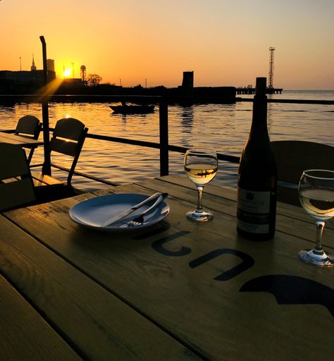 A wine glasses and bottles on a wooden table with beach sunset on the background