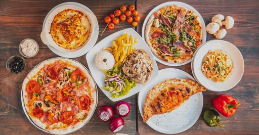A top view of different pizzas with prosciutto, greens, fries and tasty pasta