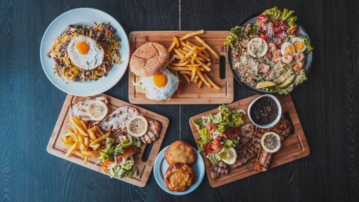 A top view of the table with grilled meat and tasty burger  steak and fries seafood bowl and pasta