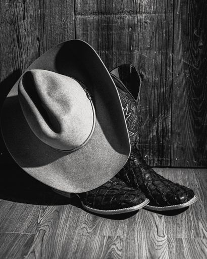 A vertical closeup of boots and an old-fashioned hat shot in grayscale