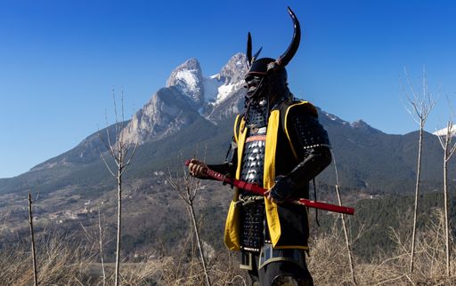 A Japanese Samurai warrior dressed in armor with a mesmerizing mountainous background