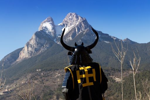 A Japanese Samurai warrior dressed in armor with a mesmerizing mountainous background