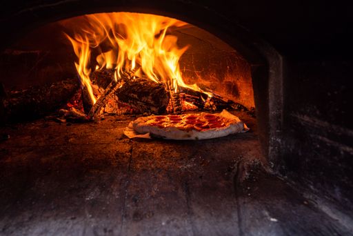 An Italian pizza in a traditional wood-fired stone oven