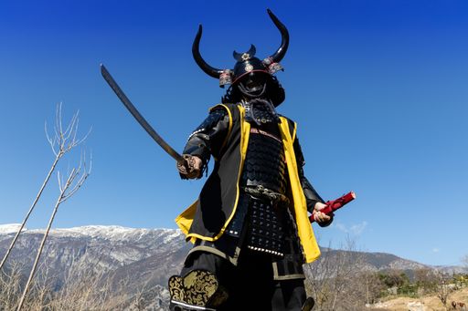 A Japanese Samurai warrior dressed in armor with a mesmerizing mountainous background