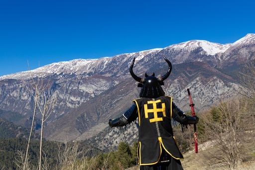A Japanese Samurai warrior dressed in armor with a mesmerizing mountainous background