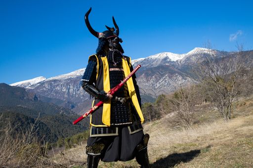 A Japanese Samurai warrior dressed in armor with a mesmerizing mountainous background