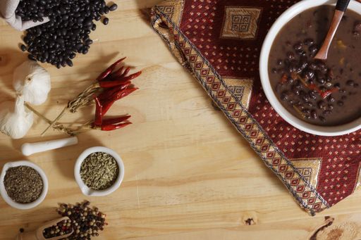 Black Bean Chili on Wooden Table With Spices and Dried Black Beans. Vintage Fabric under bowl