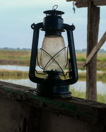 A closeup of a vintage oil lamp on a wooden fence