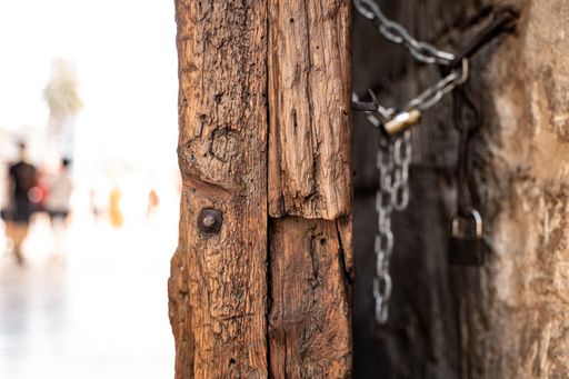 A closeup shot of an old wooden door and rusted lock chain detail