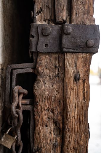 A vertical shot of an old wooden door and rusted lock detail