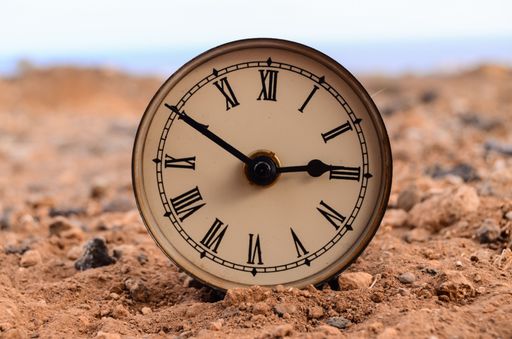 A classic analog clock in the sand on a rock desert