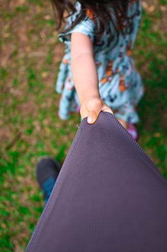 A vertical shot of a little hand pulling a man's t-shirt