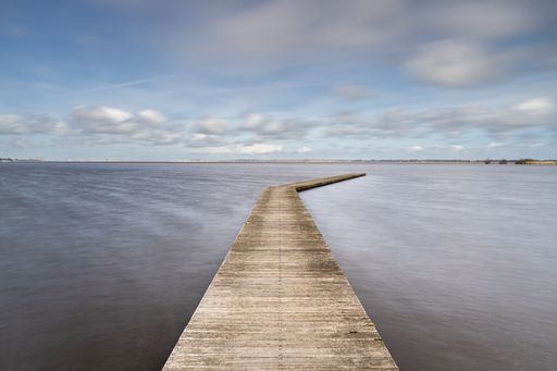 A calm deserted lake scene and a wooden jetty in the Netherlands at a landing spot for boats