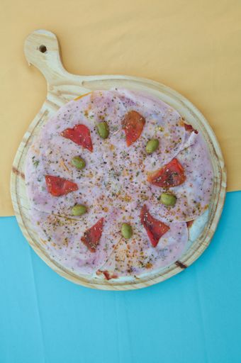 A closeup shot of a yummy pizza with ham, olives and tomatoes