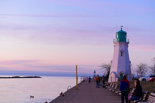 The people sitting on the benches near Port Dalhousie Range Rear Lighthouse. Ontario, Canada.