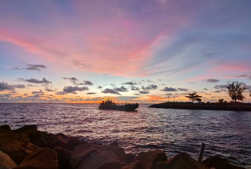 A closeup shot of a boat sailing on the sea at sunset