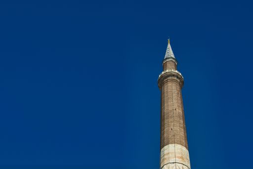 A low angle shot of a minaret against a cloudless blue sky