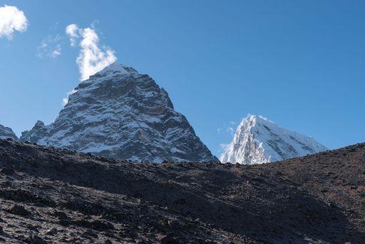 A low angle shot of snowy sharp mountains under a blue sky