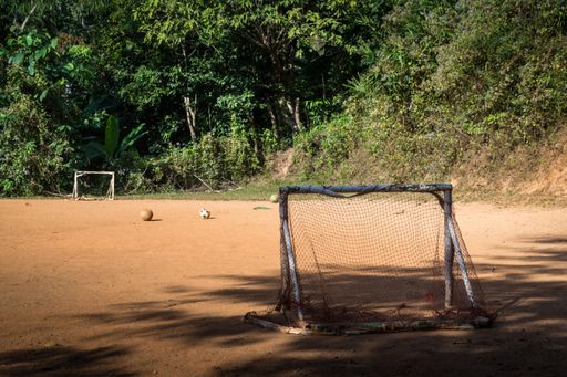An empty field with worn out goal nets and footballs