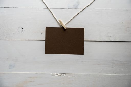 A closeup shot of an empty sign attached to a rope with a white wooden background - great for writing text