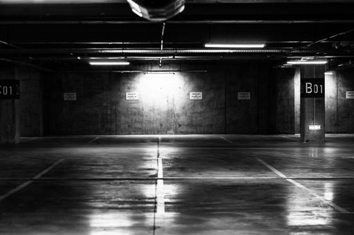 A greyscale shot of an empty underground parking lot