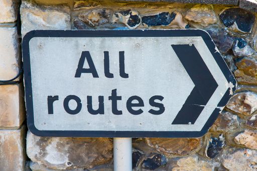 A closeup of a road sign "All routes" indicating the direction of the travel