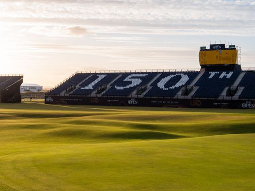 This stock photo shows a stunning view of the 12th hole of a golf course, illuminated by the golden light of the sun as it rises in a bright blue