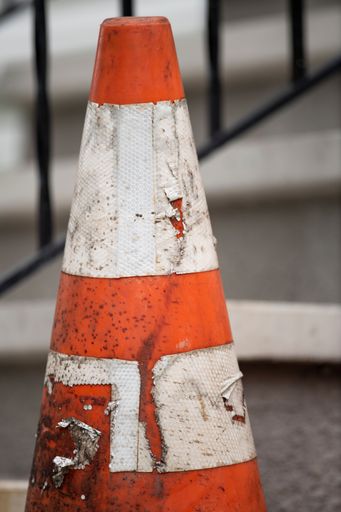 A vertical closeup of old orange and white traffic cone