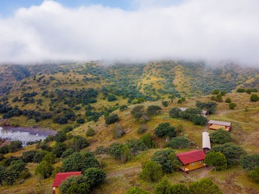 An aerial view of houses on a hill against a vast foggy mountain landscape