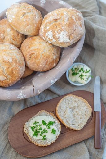 Tasty crusty round bread rolls on a cloth basket beside a knife and mayonnaise