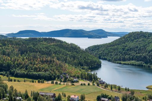 A high angle shot of rural houses on a shore of a lake surrounded by green hills
