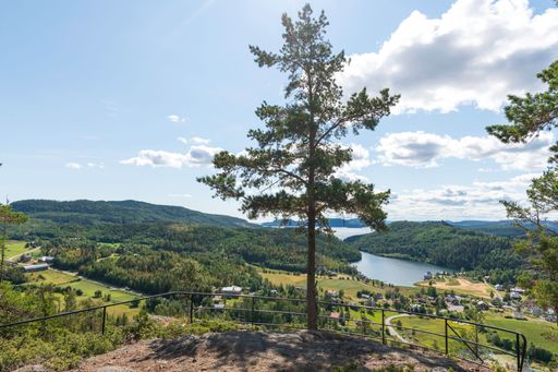 A high angle shot of a viewpoint against rural houses on a shore of a lake surrounded by green hills