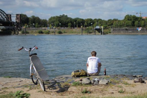 A closeup shot of a young man sitting near the water