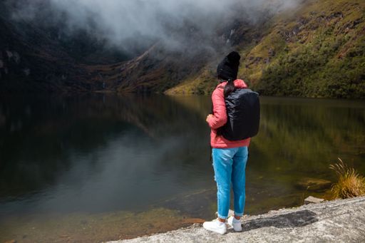 A woman posing against a lake surrounded by mountains