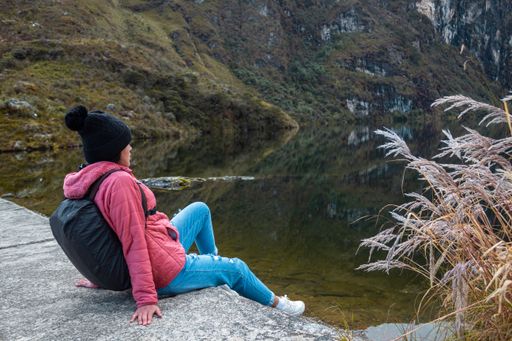A cheerful woman posing against a lake surrounded by mountains
