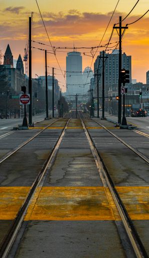 A vertical shot of a tram track rails on a view of the Boston city in sunrise