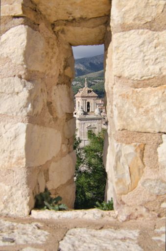 A vertical of an old building captured from a view that opens from a stone window in Caravaca De la Cruz