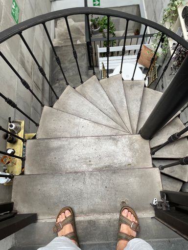 A vertical shot of round stairs with a person's feet on the top