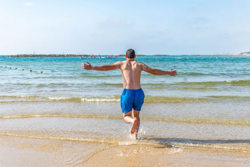 A young man with his arms extended by the sea at dawn enjoying freedom and life