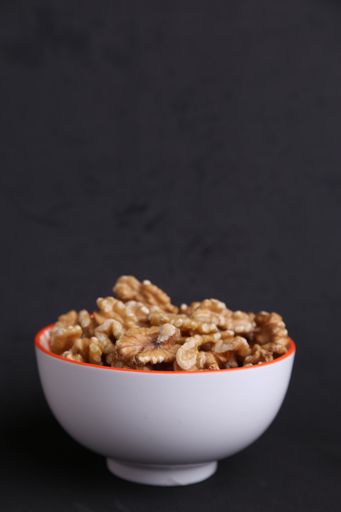 A vertical shot of some walnuts in a bowl isolated on a black background